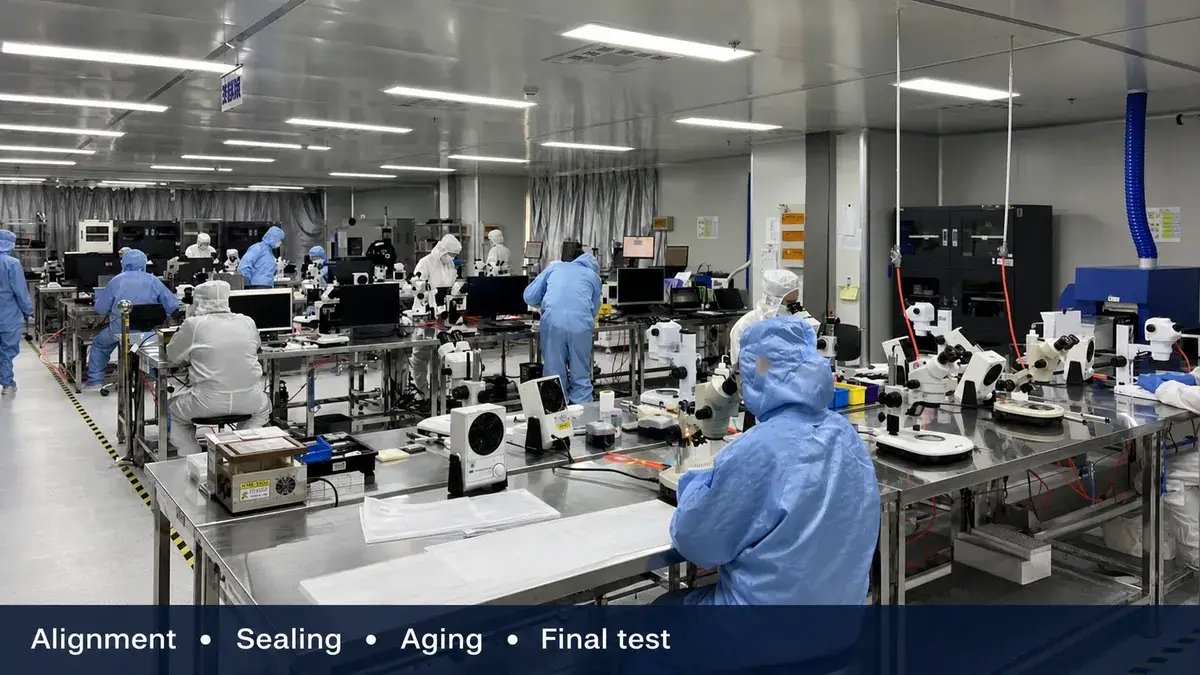 Lumexis technicians working at microscopes and assembly stations in a controlled cleanroom production area.