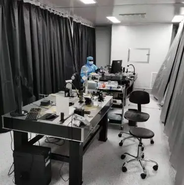 Technicians assembling and aligning laser modules at dedicated optical workstations